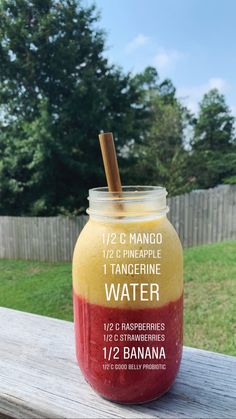 a jar filled with liquid sitting on top of a wooden table next to a fence