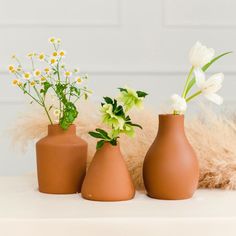 three vases with flowers in them sitting on a table