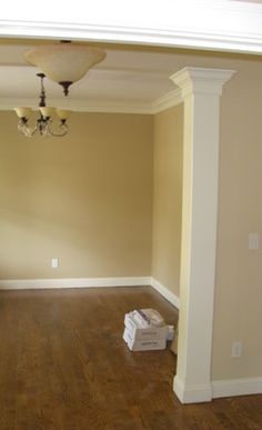 an empty room with a chandelier in the corner and hard wood flooring