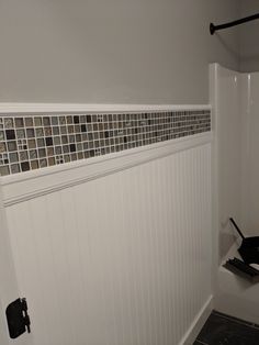 a bathroom with white paneling and tile on the shower wall next to toilet paper dispenser