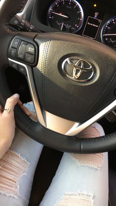 a woman is sitting in the driver's seat of a car with her hands on the steering wheel