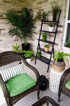 two wicker chairs sitting next to each other in front of a brick wall with potted plants on it