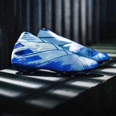 a pair of blue soccer cleats sitting on top of a black surface in the sun