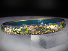 "This beautiful carved relief style bangle bracelet measures approx. 8.25\" inches in circumference and 3/8\" wide. The opening measures 2-5/8\". Featuring a lovely floral design with blue, white, green and pink enamel. This bracelet weighs 28.28 grams and is in excellent pre-owned vintage condition. Items $100 or more are shipped in a high end jewelry presentation gift box. Items less then $100 will be packaged very nicely in a pretty little box, ready for gift giving or just for safekeeping on Blue Bracelet With Intricate Design As A Gift, Jewelry Presentation, High End Jewelry, Chinese Export, Pink Enamel, Fabric Ribbon, Green And Pink, Couple Rings, Design Floral