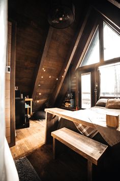 an attic bedroom with wooden walls and flooring, along with a large window looking out onto the outdoors