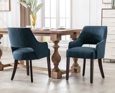 two blue chairs sitting at a wooden table in front of a vase with flowers on it