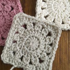 three crocheted squares sitting on top of a wooden table