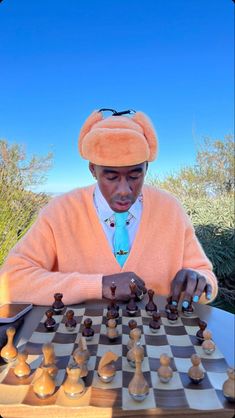 a man in an orange sweater is playing chess