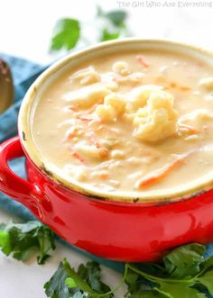 a red pot filled with macaroni and cheese soup on top of a blue napkin