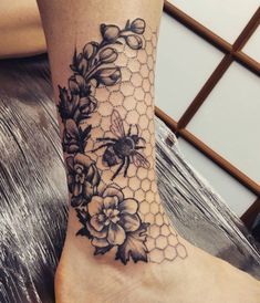 a tattoo on the foot of a woman with flowers and honeycombs around it