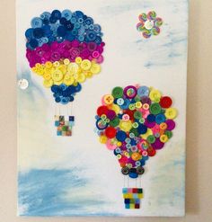 two hot air balloons made out of buttons on a white board with blue sky and clouds in the background