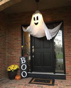 a front door decorated for halloween with a ghost hanging from the ceiling and a boo sign