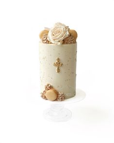 a white cake with gold decorations and a cross on top