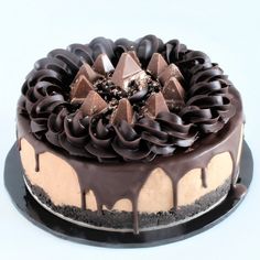 a cake with chocolate icing and toppings on a black platter against a white background