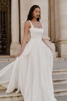 a woman in a white dress is standing on some steps