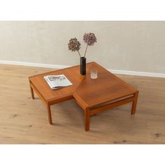 a wooden table with two small tables on each side and flowers in a vase on top