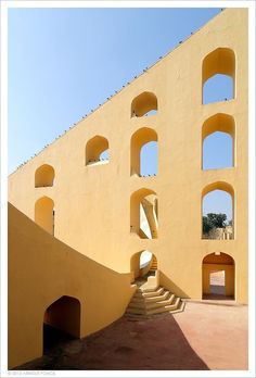 a yellow building with arched windows and stairs