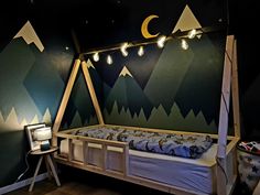 a bedroom with mountains painted on the wall and lights hanging from the ceiling above it