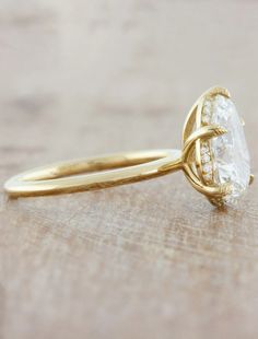 a gold ring with a white diamond in the center on a wooden surface, close up