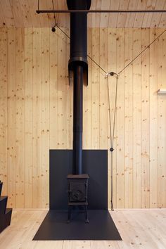 a black stove sitting in the middle of a room next to a wooden paneled wall