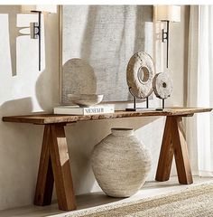 a table with two vases on it in front of a mirror and lamp shade