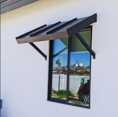 a black car is parked in front of a white building with an awning over it