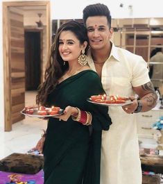 a man and woman standing next to each other holding plates with food on them in their hands