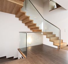 a staircase with glass railing and wooden handrails in a modern style home setting