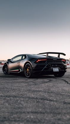 a black sports car is parked on the pavement in front of an airport runway at sunset