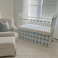 a baby crib in the corner of a room next to a chair and window