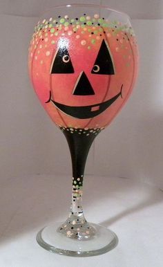 an orange painted wine glass with a black face and sprinkles on it