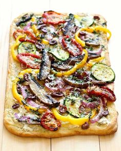 a square pizza topped with lots of veggies on top of a wooden table