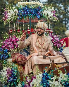 a man sitting on top of a horse drawn carriage covered in flowers and garlands