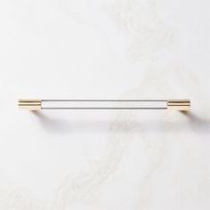 two brass handles on a white marble wall with gold bars in the middle and bottom