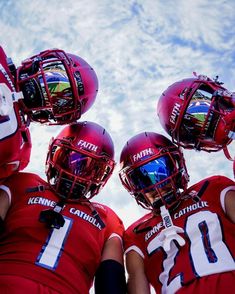 three football players in red uniforms with helmets on their heads are looking at the sky