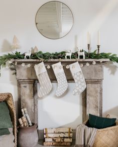 christmas stockings hanging from the mantle in front of a fireplace with candles and other decorations