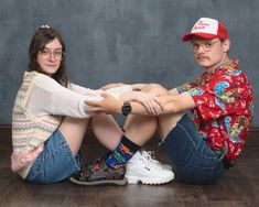 a man and woman sitting on the floor with their arms around each other's legs