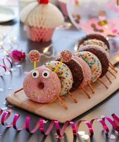 there are donuts with sprinkles on them sitting on a wooden board