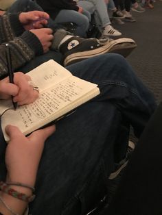 two people sitting on a bus with one writing in a book and the other holding a pen