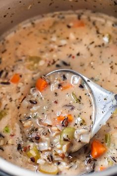 a ladle full of soup is being held up by a metal spoon in the pot