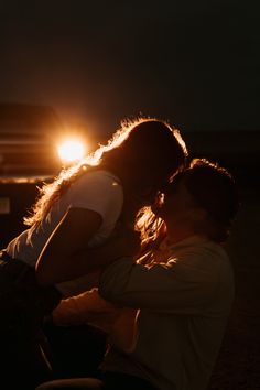 a man and woman sitting next to each other in front of a truck at night