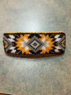 a yellow and black beaded bracelet sitting on top of a table