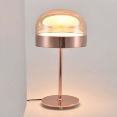 a table lamp that is on top of a white surface and has a light in the middle