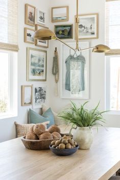 a wooden table topped with a bowl filled with potatoes next to a potted plant