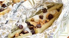 two hotdogs covered in chocolate chips and melted marshmallows on tin foil