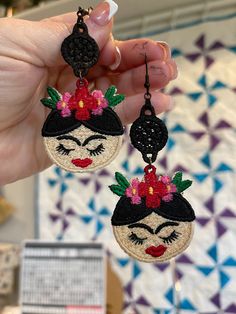 a pair of handmade earrings featuring a woman's face with flowers in her hair