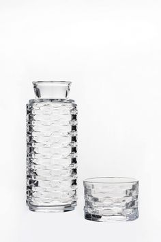 two clear glass vases sitting next to each other on a white surface with no one around them