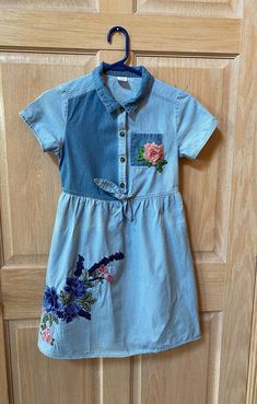 Girls size 10-12 denim dress with floral appliqué. Spring Cotton Dress With Floral Applique, Blue Cotton Dress With Floral Applique, Fitted Denim Dress With Floral Embroidery, Spring Denim Blue Floral Embroidered Dress, Medium Wash Cotton Denim Dress With Floral Embroidery, Summer Denim Dress With Floral Embroidery, Spring Denim Dress With Floral Embroidery, Spring Floral Embroidered Medium Wash Denim Dress, Spring Medium Wash Denim Dress With Floral Embroidery