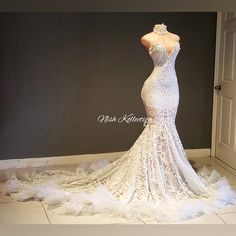 a white wedding dress on display in front of a black wall with an open door