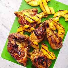 grilled chicken and pineapples on a green cutting board next to sliced bananas